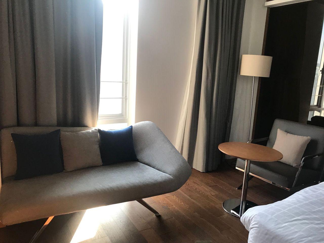 Cozy seating area with a light grey couch and a small round table at Dongdaemun Novotel Ambassador Hotel.